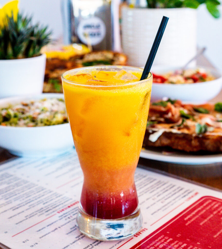 a photo of a fluffy orange mule mocktail from Uncle Nicky's. A tall glass on a table filled with orange juice and grenadine. 